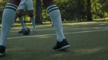 Spor ayakkabılı iki gencin halka açık bir parkta futbol oynarken çekilmiş el kamerası görüntüleri.