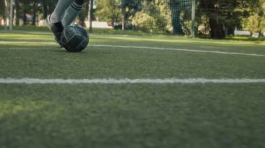 Parktaki çimenlik alanda oynarken spor ayakkabısı ve çorap giyen tanınmayan erkek futbolcunun düşük kesiminden.