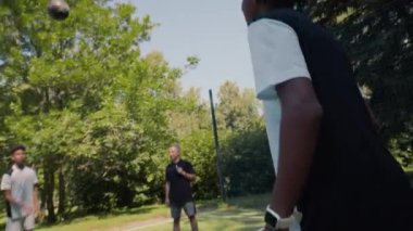 İki genç Afrikalı Amerikalı futbol oyuncusu güneşli bir günde Kafkasyalı yetişkin erkek koç ile sahada antrenman yaparken...
