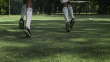 Açık havada futbol oynayan, top süren ve kalede gol atan tanınmamış iki gencin düşük kesimli çekimi.