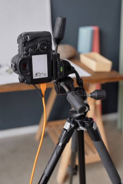 Profesyonel DSLR kamerasının dikey arkaplan görüntüsü fotoğraf stüdyosundaki tripoda monte edilmiş ürün fotoğrafçılığı kurulumunun fotoğraflarını çekiyor.