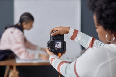 Back view closeup of African American woman holding professional DSLR camera and taking pictures in photo studio copy space clipart