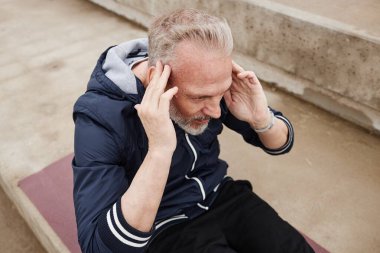 Üst düzey bir adamın yoga minderinde mekik çekerken, beton zeminde kas kaslarını güçlendirirken, şehir parkındaki günlük antrenman sırasında.