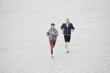 Tanımlanamayan yaşlı erkek ve kadının geniş açı çekimi her gün birlikte şehir parkında koşmaya devam ediyor.