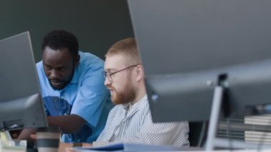 İki genç etnik çeşitlilikte programcı ofiste kod sorununu çözerken sohbet ediyorlar.