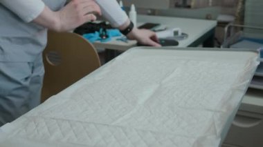 Bilinmeyen kadın veterinerin tek kullanımlık tıbbi kağıtlarını masaya serip stetoskop, termometre ve çip tarayıcı gibi inceleme araçlarını hazırlamaya başlaması.