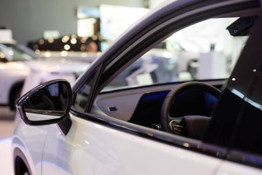 Galeri merkezinde vitrini açık olan parlak beyaz arabanın dikiz aynası.