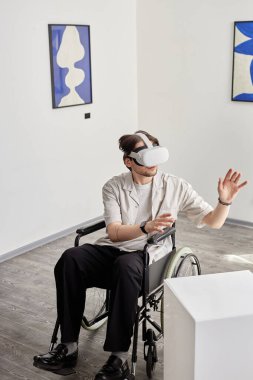 Engelli bir adamın dikey geniş açılı portresi VR teknolojisi kullanıyor ve müze ortamında dijital sanat eserleriyle etkileşimde bulunuyor.