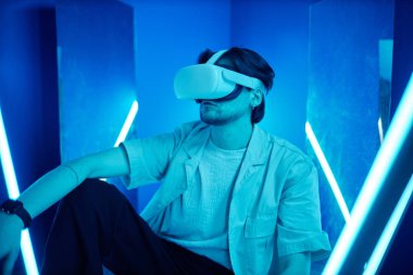 VR kulaklık takan bir adamın portresi neon ışıkların altında dijital siber uzay deneyimi yaşıyor.