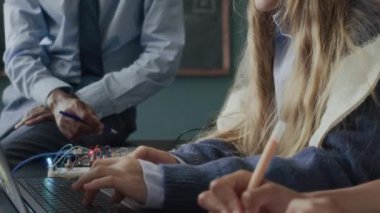 Modern sınıfta programlama ve mühendislik dersi alırken, beyaz kız öğrencilerin dizüstü bilgisayarda kod yazmalarını ve siyahi erkek öğretmenlerin yardım etmelerini.