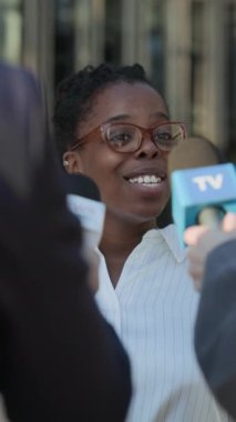 Siyahi kadın girişimcinin açık hava basınına röportaj verirken omuz üstü çekimleri.