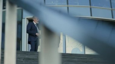 Modern binanın dışındaki merdivenlerde duran ve sohbet eden farklı etnik çeşitlilikte kadın ve erkek iş ortaklarının düşük açı çekimi.