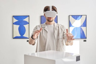 Müzedeki modern sanat sergisi sırasında görünmez dijital sanat eserleri ile etkileşim halinde olan VR 'ı takan adamın minimal portresi, kopyalama alanı