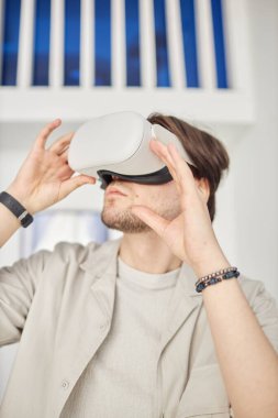 VR kulaklık kullanan bir adamın dikey portresi fütürist akıllı ev veya modern sanat müzesinde minimum beyaz ayar