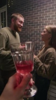 Arkadaşların sıcak yaz partisinde terasta sohbet ederken kadehlerini tokuşturdukları dikey görüntüler.