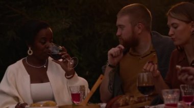 Geceleri arka bahçede akşam yemeği yerken çok kültürlü gençlerin sohbet edip kadehlerini kaldırmaları.