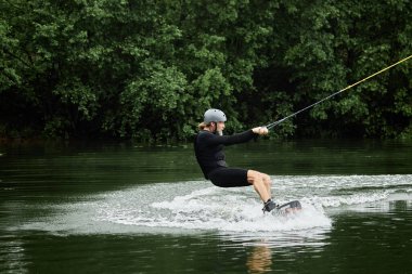 Sakallı, olgun bir adamın manzaralı orman gölü fotokopi alanındaki su sporları ve sörf sporlarının keyfini çıkartırken görüntüsü.