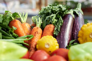 Çiftçi pazarında canlı bir şekilde sergilenen havuç, patlıcan, domates ve sarı kabak gibi taze organik sebzeler.
