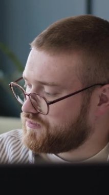 Z Geni, gözlüklü, beyaz bir adam kahve fincanını kaldırıyor ve bilgisayarla ofisinde daktilo yazıyor.