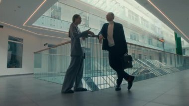 Modern iş merkezinde cam parmaklıkların önünde el sıkışan ve dans etmeye başlayan tam teşekküllü iş çifti.