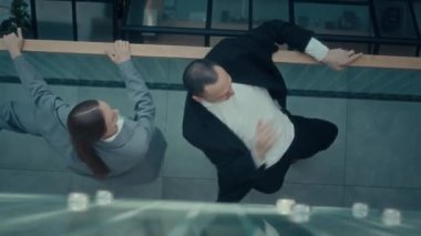 Modern iş çiftlerinin modern iş merkezinde cam parmaklıklarla modern dans gösteriminin yukarıdan aşağı görüntüsü.