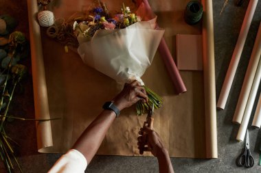 Masadaki güzel çiçek buketinin detaylarını bitiren erkek ellerinin en küçük üst görünümü kağıt arka plan kopyalama alanı ile birlikte.