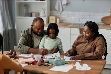 Aile, sanat ve zanaat yaparak birlikte vakit geçirmekten zevk alıyor. Ebeveynler ve çocuklar iş birliği yapıyor ve renkli sanat eserleri yaratıyorlar.