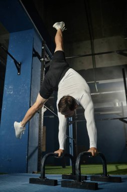 Amuda kalkmış kaslı adamın dikey poziyonu. Bir bacağı yanda. Jimnastik teknikleri.