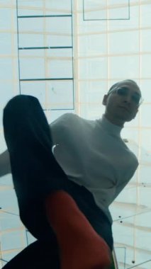 Erkek dansçının modern kapalı alanda cam tavan altında sanatsal performans sergilediği dikey görünüm.
