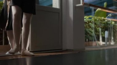 Tanımlanamayan üç bale dansçısından oluşan bir grup siyah tayt ve beyaz tayt giyerek yerden tavana pencereli, ellerinde bale ayakkabıları taşıyan geniş stüdyoya geliyor.