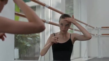 Kafkas genç balerin aynanın önünde duruyor ve bale stüdyosunda prova yaparken saçlarını düzeltiyor.