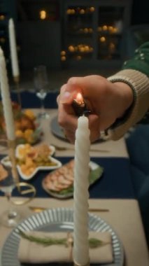 Ailesiyle ya da arkadaşlarıyla Noel kutlaması partisi için şenlikli bir yemek masası hazırlarken yeşil hırka giymiş isimsiz birinin dikey kesilmiş fotoğrafı.