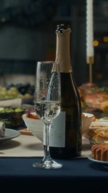 Dikey olarak dekore edilmiş Noel yemeği masası aromalı yemekler, mumlar, seçici odak noktasında bir şişe köpüklü şarap.