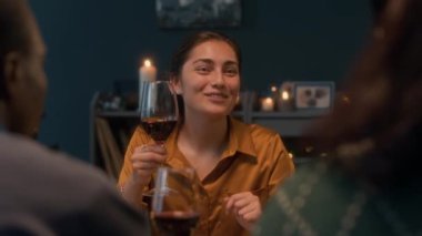 Omzundan yukarı kaldırılmış beyaz kadın kadehini kaldırmış kırmızı şarap kadehiyle yemek masasında tost kaldırırken sıcak sıcak atmosferde arkadaşlarıyla Noel 'i kutlarken.