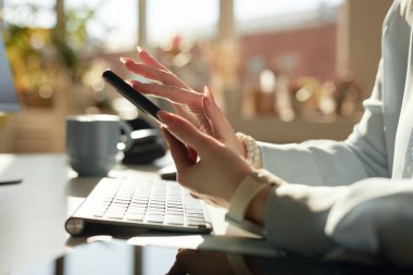 Yan görüntüde cep telefonu tutan kadınların elleri ve iş yerinde güneş ışığıyla aydınlatılan sosyal medya, boşluğu kopyala
