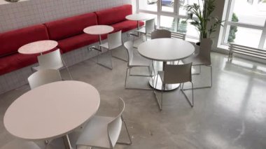 Basit beyaz mobilyalar ve kadife kırmızı koltuklar olan minimalist kafeteryanın iç çekimleri yok.