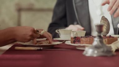 19. yüzyıldan kalma zarif elbiseli bir kadının ekmeklere tereyağı sürerken zengin yemek odasında soylu insanlarla klasik dekorlu çay partisi yaparken görüntüsü.