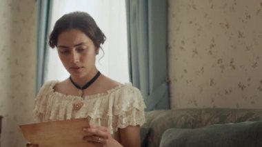 19. yüzyılda parşömen kâğıdında mektup okuyan ve kötü haber aldıktan sonra döşeme üzerinde bayılan endişeli, beyaz bir kadının orta boy fotoğrafı.