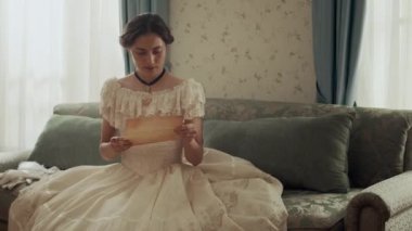 Parşömen kağıdına yazılan kötü haberden sonra döşeme üzerinde bayılan 19. yüzyıl genç kadınının orta boy fotoğrafı.