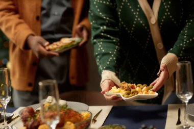 Cropped shot of woman serving cheese platter with olives and nuts as snack to wine on dining table and man helping while preparing for family Christmas dinner, copy space clipart