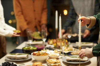 Cropped shot of woman lighting candlestick while serving festive dinner together with family on Christmas Eve, copy space clipart