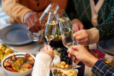 Cropped shot of people raising toast clinking glasses with champagne at friends gathering while celebrating Christmas together at home dinner, copy space clipart