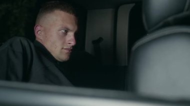 Tutuklandıktan sonra polis arabasının arka koltuğunda otururken kelepçeleri çıkarmaya çalışan Kafkasyalı erkek suçlu.