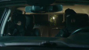 İki tehlikeli soyguncu kafalarına ve yüzlerine siyah maskeler takıp gece suç işlerken arabadan iniyorlar.
