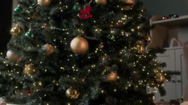Süsler, çelenkler, hediye kutuları ve oyuncaklarla süslenmiş yapay Noel ağacı oturma odasında.