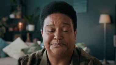 Oturma odasında oturmuş blog için video kaydederken kıdemli Afrikalı Amerikalı kadın etkisinin yakın plan fotoğrafı.
