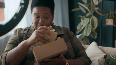 Modern yaşlı siyahi kadın blogcunun güzellik ürünü video incelemesini kaydettiği orta boy bir fotoğraf.