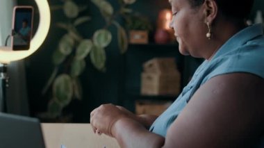 Yaşlı Siyahi kadın blogcu lamba sahibine yerleştirilen akıllı telefondan cihaz inceleme videosu kaydediyor.