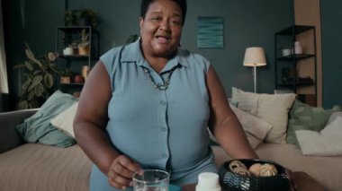 Yaşlı Siyahi kadın blogcu elinde ilaç organizatörüyle sağlık ve beslenme takviyeleri hakkında video kaydediyor.