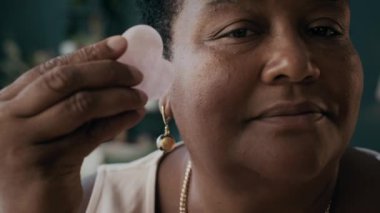 Afrika kökenli Amerikalı güzellik blogcusu gua sha yüz masajı yapmayı gösteriyor.